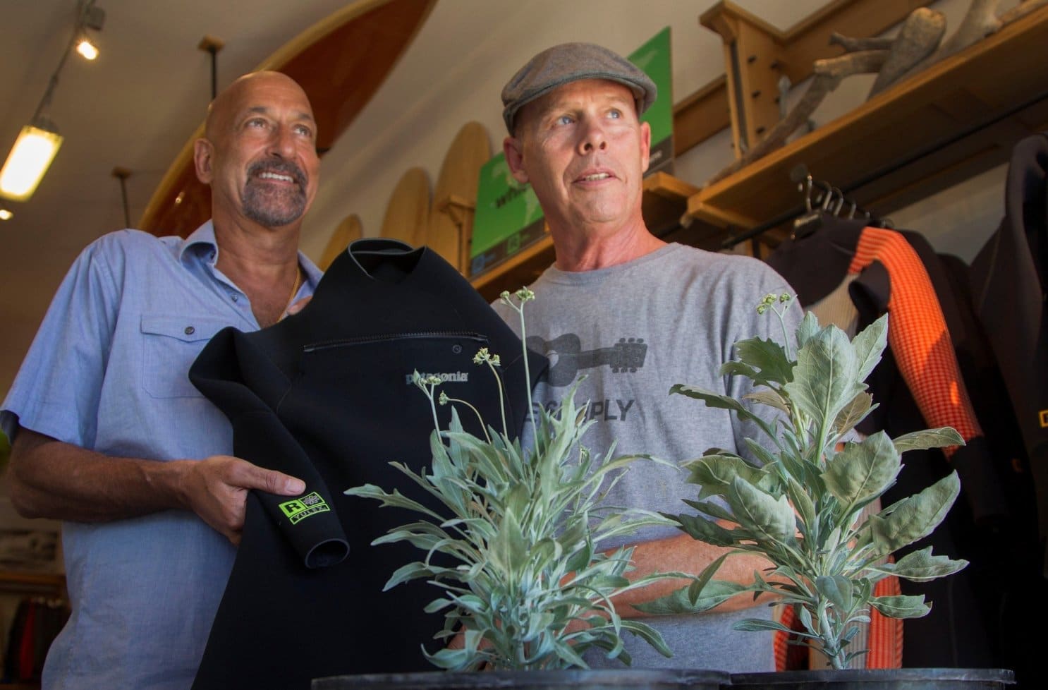 eric and jeff holding wetsuit behind guayule plant